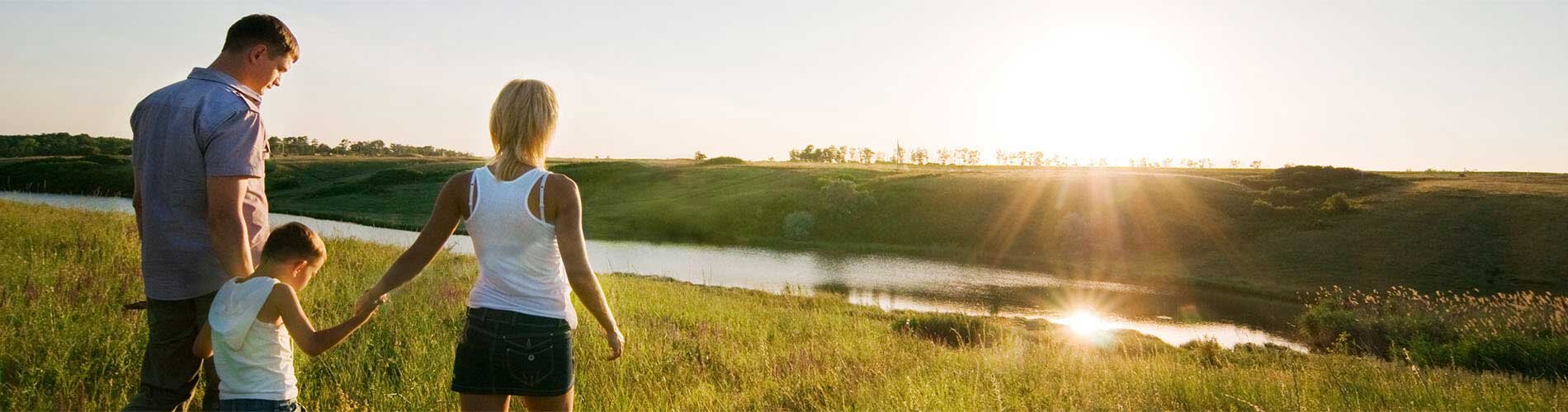 Family walking through grass toward the sunset